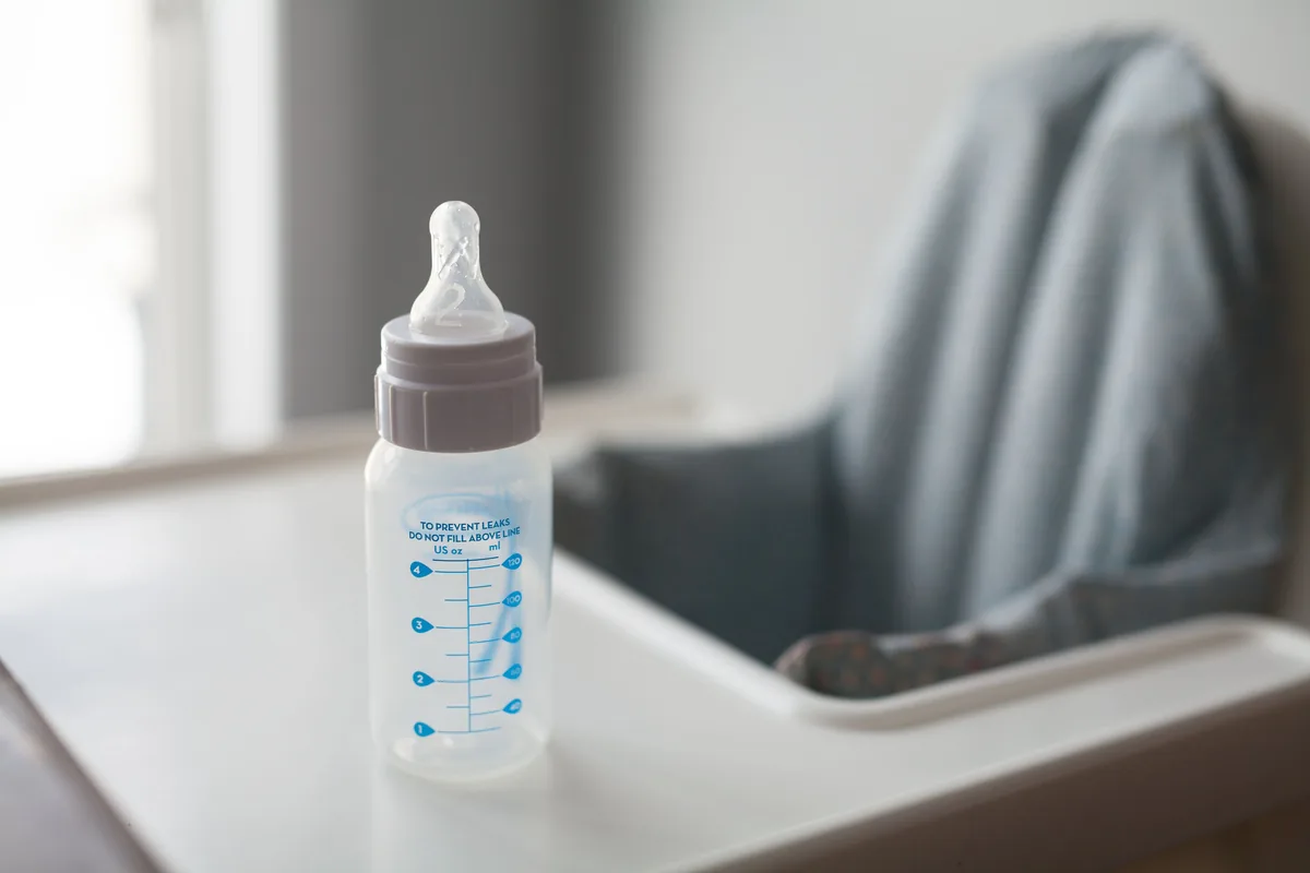 Leere Babyflasche auf dem Tablett eines Hochstuhls
