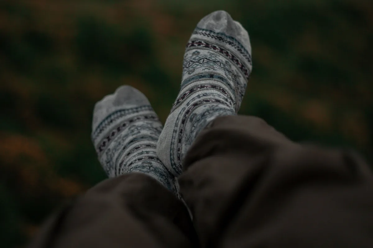 Hochgelegte Füße in gemusterten Socken vor einer abendlichen Landschaft
